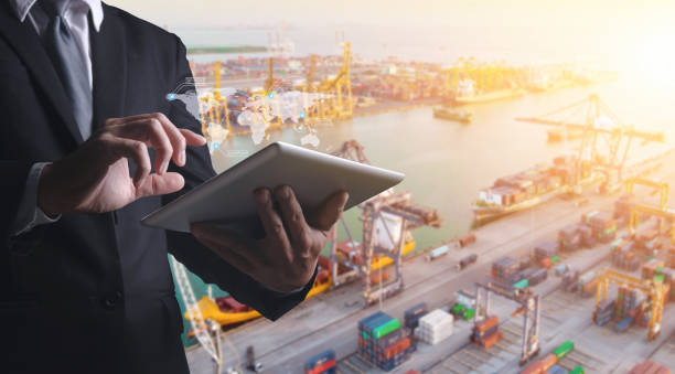 Douple exposures of Businessman touching tablet for analyze stock at logistics port and world map with logistic network distribution on background, transportation trading business concept, stock photo