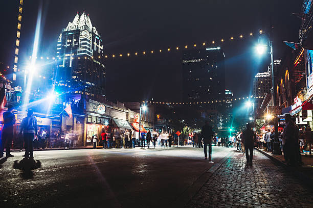 Downtown Austin at Night on Sixth Ave Weekends finds Austin, Texas 6th Avenue closed to cars, allowing foot traffic to easily come and go from the city nightlife, bars, and clubs.  Horizontal, long exposure image. austin texas stock pictures, royalty-free photos & images