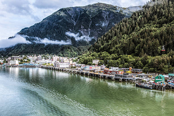 Downtown Juneau, Alaska Expansive view of downtown Juneau and waterfront, Alaska. Morning, waterfalls and fog nestled in the mountains. Mount Roberts tram operating at right. alaska stock pictures, royalty-free photos & images