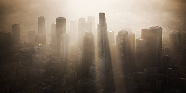Downtown Los Angeles Dramatic rays of light beam through the Los Angeles skyline as the sun sets and the marine layer rolls in. smog stock pictures, royalty-free photos & images