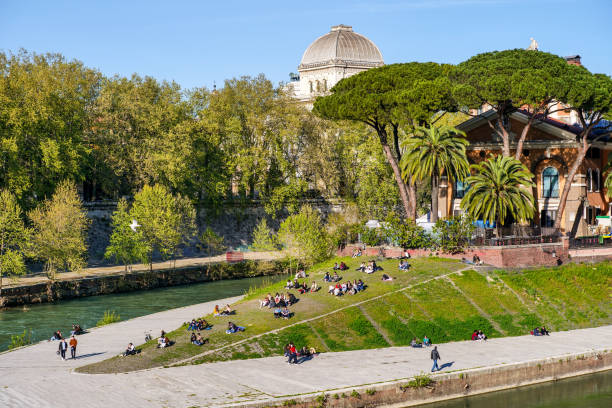 Dozens of people enjoy a sunny day along the Tiber River near the Jewish Ghetto in Rome stock photo