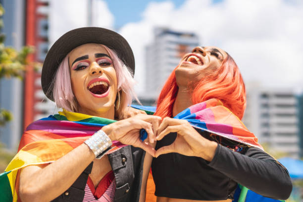 drag reines enveloppées dans le drapeau lgbt et montrant la forme de coeur avec des mains - homophobie photos et images de collection