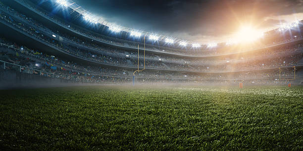 Dramatic american football stadium A wide angle panoramic image of a outdoor american football stadium full of spectators under evening sky. The image has depth of field with the focus on the foreground part of the pitch. The view from center of the field. american football field stadium stock pictures, royalty-free photos & images