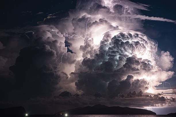 dramatic cloud and thunderstorm over an island. multiple lightni - dramatische lucht stockfoto's en -beelden