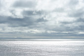 istock Dramatic cloudy sky over dark water ripple surface sea, sunlight 609819554