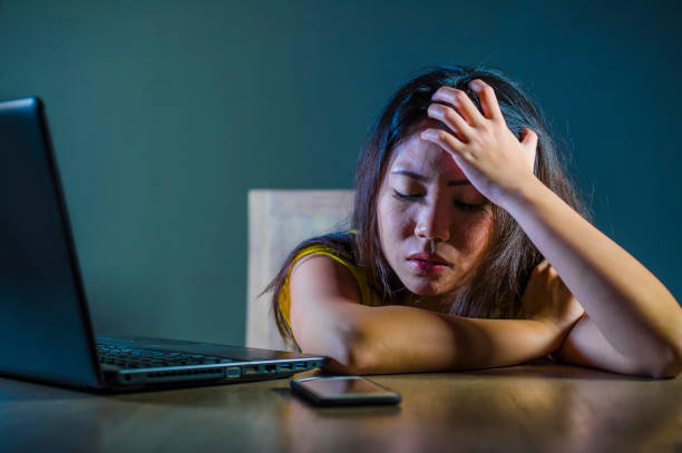 dramatic portrait scared and stressed Asian Korean teen girl or young woman with laptop computer and mobile phone suffering cyber bullying stalked and harassed with internet password hacked  victim stock pictures, royalty-free photos & images