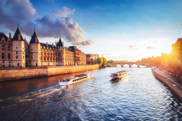 dramatic sunset over river seine in paris, france, with conciergerie and cruise boats. - paris imagens e fotografias de stock