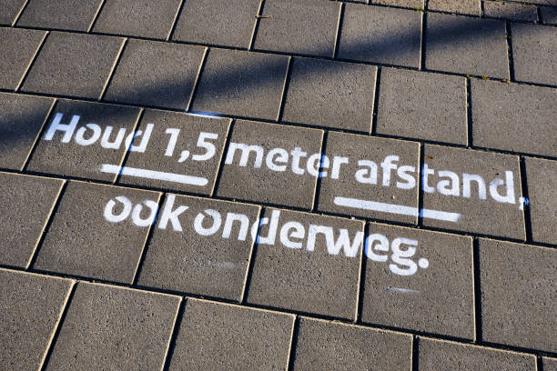 tekenen op bestrating in nederlandse letters betekent: 'houd 1,5 meter sociaal afstand, ook op de weg'. coronavirus maatregelen en regels - coronatest netherlands stockfoto's en -beelden