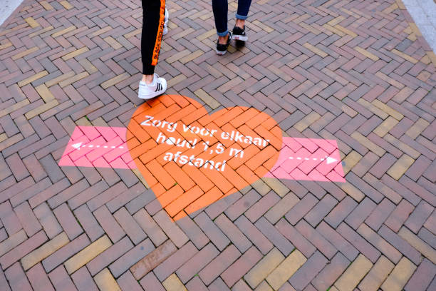 tekenen op straat in het nederlands, zorgen voor elkaar houden 1,5 m sociale distantiëring, winkelgebied. mensen die lopen - coronatest netherlands stockfoto's en -beelden