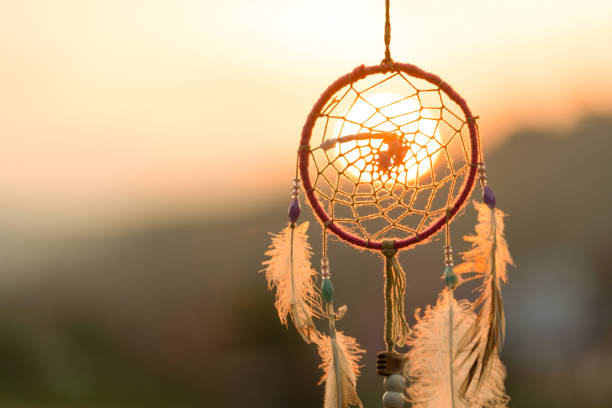 Dream cathcher amulet with sunset in background.Dream catcher is a handmade willow hoop woven to a web or literally  includes such features as feathers and beads stock photo