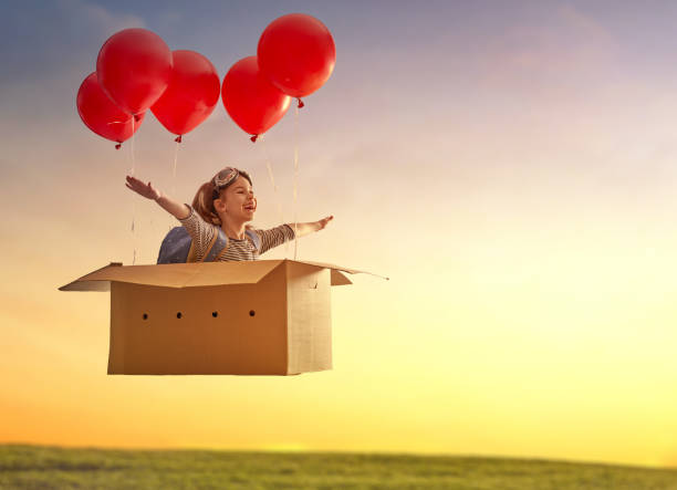 Dreams of travel Dreams of travel! Child is flying in cardboard box with air balloons. one girl only stock pictures, royalty-free photos & images