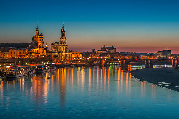 Dresden, Bruehl Terrace, Elbe River Reflections at Dusk, Germany Dresden Bruehl Terrace with Semper Opera and Frauenkirche against blue and peach color sky. Evening illumination reflections in the Elbe River. Saxony, Germany. dresden germany stock pictures, royalty-free photos & images