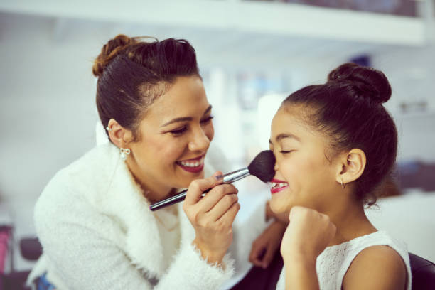 Dressing room smiles Shot of a mother applying makeup to her cute little girl in a dressing room beauty pageant stock pictures, royalty-free photos & images