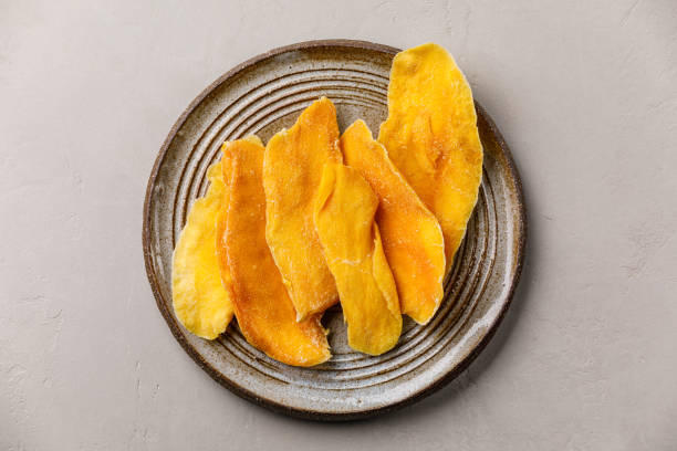 Dried dehydrated Mangoes on plate on gray concrete background stock photo