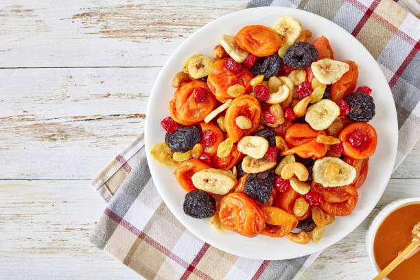 dried Fruits, Nut honey, top view, flat lay dried Fruits and Nut Mix bowl - banana slices, apricots, raisins, prunes, cherries and cashew on a rustic table with honey in a bowl, horizontal view from above, close-up, flatlay dried fruit stock pictures, royalty-free photos & images