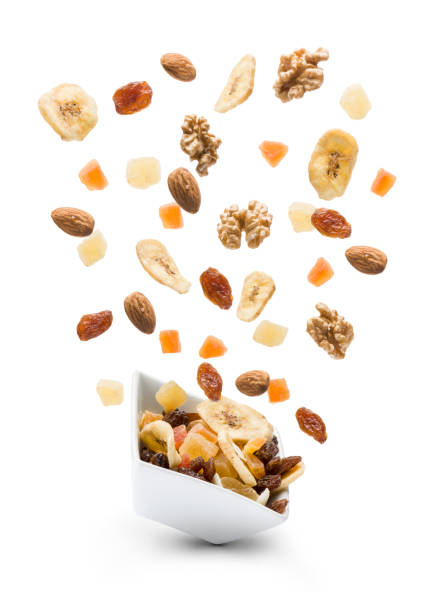 dried fruits Dried fruits jumping out white bowl on white background dried fruit stock pictures, royalty-free photos & images