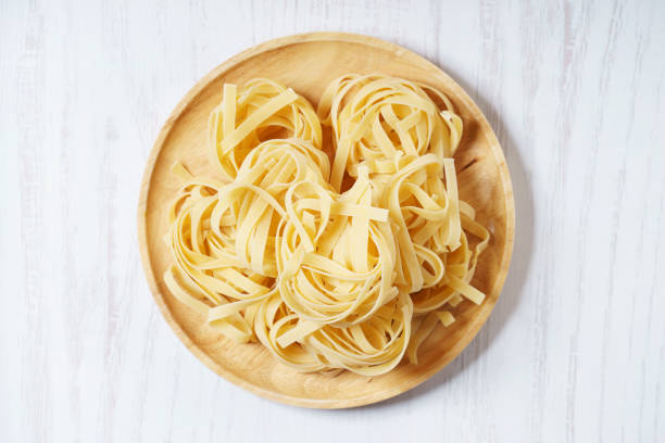 dried pasta dried linguine pasta on wooden plate uncooked pasta stock pictures, royalty-free photos & images