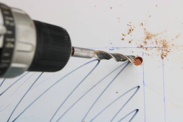 Drilling hole in a white wooden board stock photo