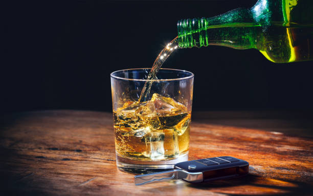 Drinking and driving concept. Car key and alcohol glass on wooden background. 3d illustration. stock photo