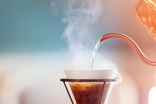 Drip coffee, barista pouring water on coffee ground with filter