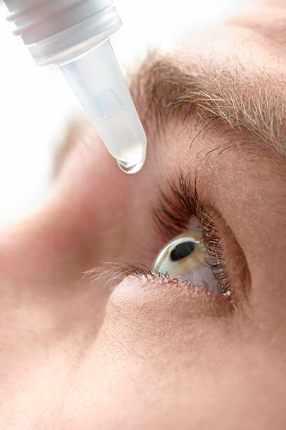 Dripping eye with eyes drops stock photo