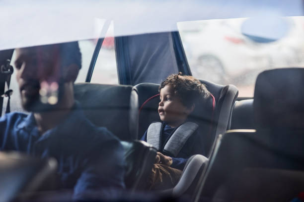 Drive safely with your precious cargo Shot of a little boy sitting in a car seat while his father drives car safety seat stock pictures, royalty-free photos & images