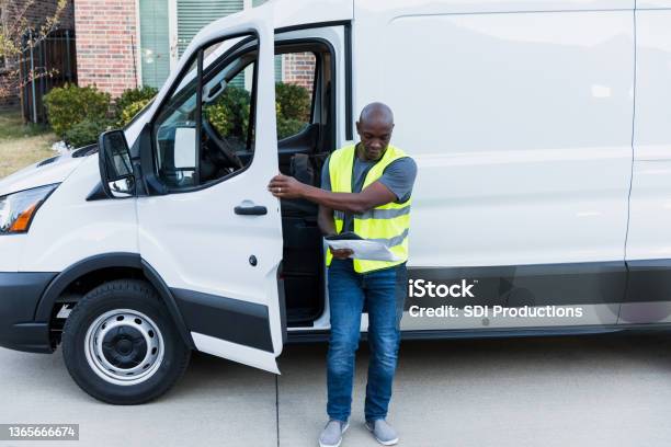 Driver looks at package while closing door of van