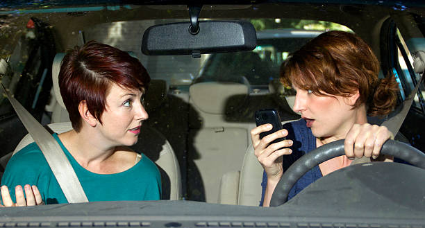 Driver Texting And Driving in a Car with a Passenger stock photo