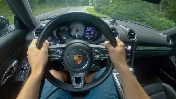 POV: Driving down empty country road winding through the forest in a new Porsche stock photo