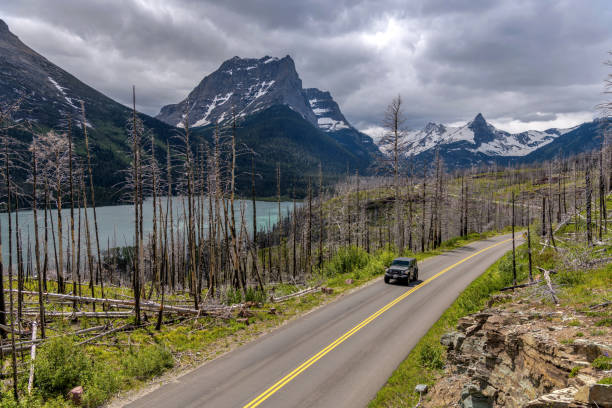 Driving on Go-To-The-Sun Road - A SUV driving down the winding Go-To-The-Sun road at side of Saint Mary Lake on a stormy Spring day in Glacier National Park. stock photo