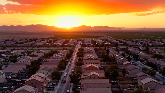 Aerial shot of a housing development bordering farmland in Maricopa, Arizona at sunset.
