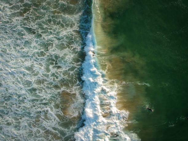 Drone view of beautiful turquiose sea waves breaking on sandy coastline. Aerial shot of golden beach Drone view of beautiful turquiose sea waves breaking on sandy coastline. Aerial shot of golden beach meeting deep blue ocean water and foamy waves sea foam stock pictures, royalty-free photos & images
