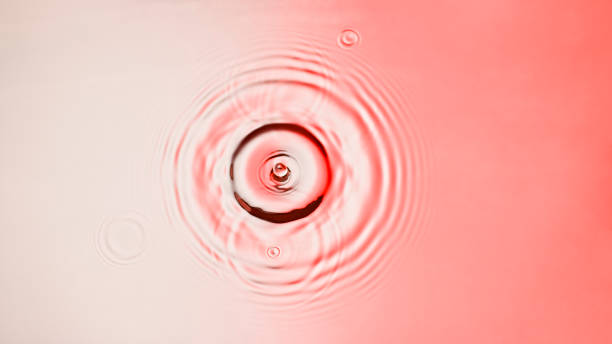 Droplet creating a splash and ripples when hitting the surface stock photo
