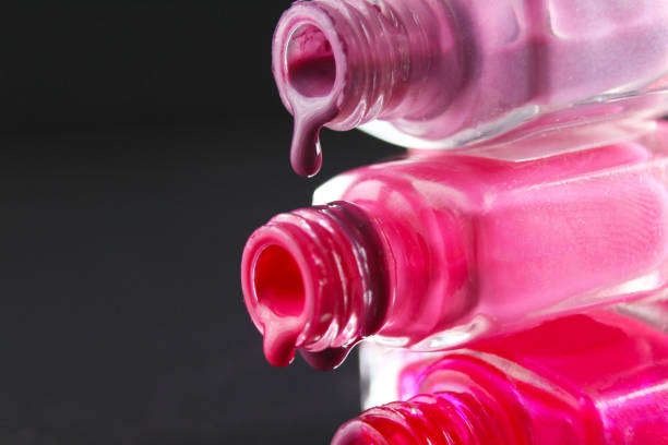 de dalingen van rode bebaarde roze nagellakstroom van de fles van de fles op een zwarte donkere achtergrond met een copyspace - nail polish bottle close up stockfoto's en -beelden