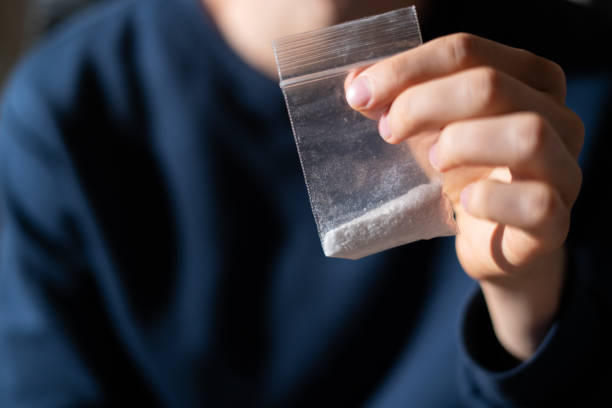 drug addict hands holding a small package with white powder drug addict hands holding a small package with white powder amphetamine stock pictures, royalty-free photos & images