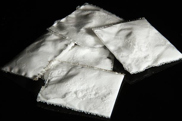 Drug Packets Clear plastic baggies containing a white powder.  They are against a black background. cocaine stock pictures, royalty-free photos & images