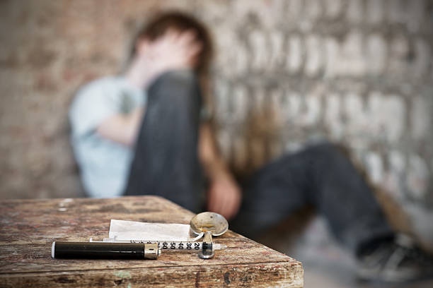 Drug paraphernalia with blurred addict behind Drug addiction crisis heroin stock pictures, royalty-free photos & images