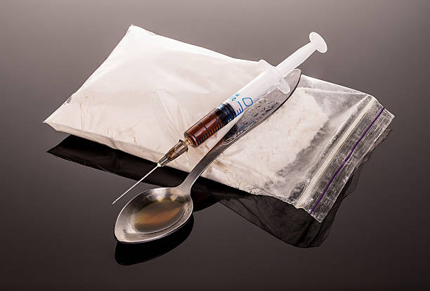 Drug syringe and cooked heroin on spoon close-up. Drug syringe and cooked heroin on spoon close-up on a brilliant black mirror background. mephedrone stock pictures, royalty-free photos & images