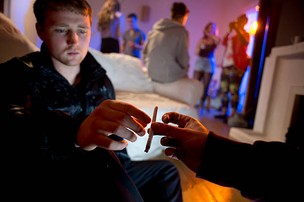 drugs and booze at a house party young man passing a joint  at a house party cannabis narcotic stock pictures, royalty-free photos & images