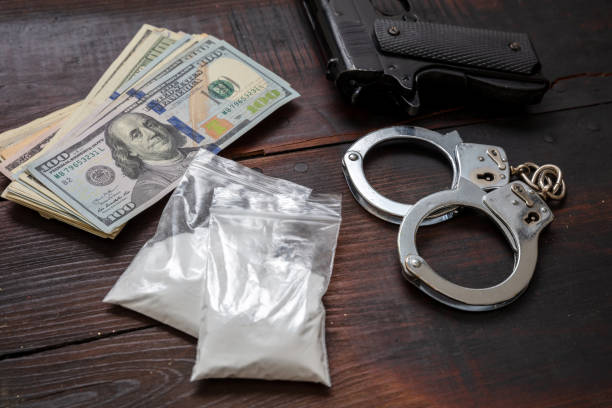 Drugs narcotics possesion and use, arrest and punishment for illegal business concept. Cocaine plastic packets, pistol US dollars and handcuffs. stock photo