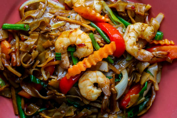 Drunken noodles, pad kee mao, with prawns, basil, chilii, peppers and green beans. stock photo