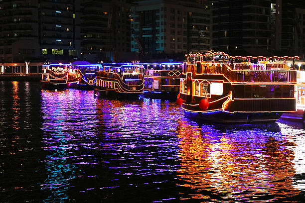 Dubai Marina Dhow Cruise Boats at Night Dubai Marina Dhow Cruise traditional wooden boats lit at night with reflections in the water. dhow stock pictures, royalty-free photos & images