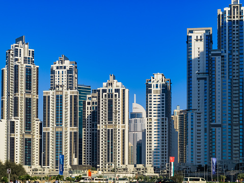 Dubai, United Arab Emirates - February 05, 2015: a view of the Skyline as seen from a Dubai Metro Station. The tall concrete skyscrapers all appear to be bunched together. In the centre, between the blocks, the Address Hotel appears smaller than the rest of the buildings: it is only because of the distance. Photo shot in the bright afternoon sunlight; horizontal format. Copy space.