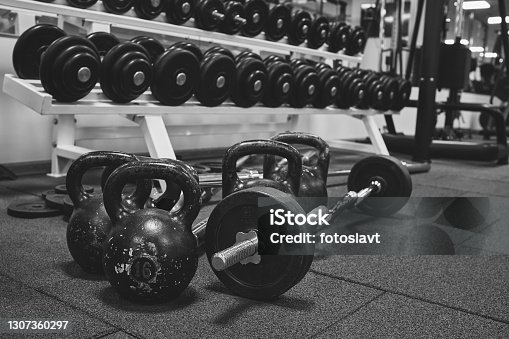 istock Dumbbells and kettlebells on a floor. Bodybuilding equipment. Fitness or bodybuilding concept background. black and white photography 1307360297