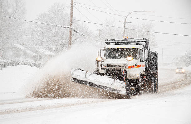 dumptruck with plow plowing snow during northeaster stock photo