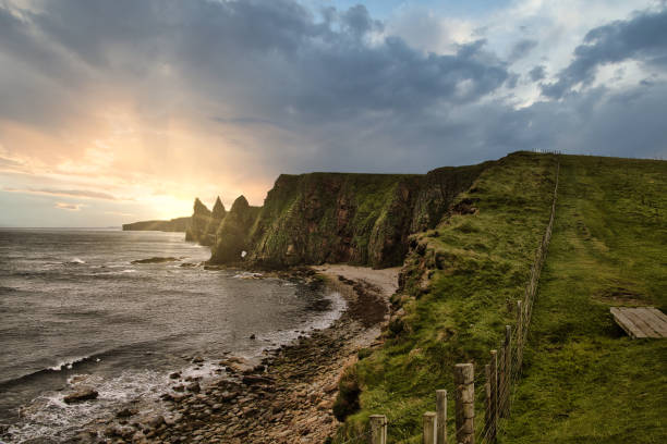Duncasby head at sunset, cliffs and coastline Duncasby stacks at sunset, head, cliffs and coastline, cloudy and storm wheather, rainy, green, lucious, sheep pasture caithness stock pictures, royalty-free photos & images