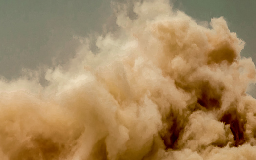 Dust clouds and flying rock particles during detonator blast on the construction site in the middle east