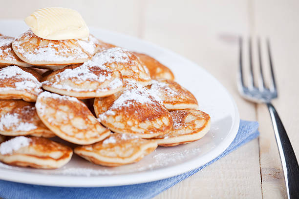 Dutch food: 'Poffertjes' or little pancakes 'Poffertjes': little Dutch pancakes with butter and powdered sugar. Shallow depth of field, focus on lump of butter. dutch culture stock pictures, royalty-free photos & images