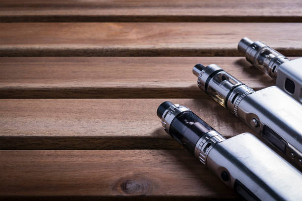 e cigarette for vaping devices over a wooden background. vape pens for sale stock pictures, royalty-free photos & images