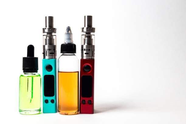 e- liquid, e-juice in the bottles and e-cigarette (vape)  isolated on the white background with copyspace stock photo